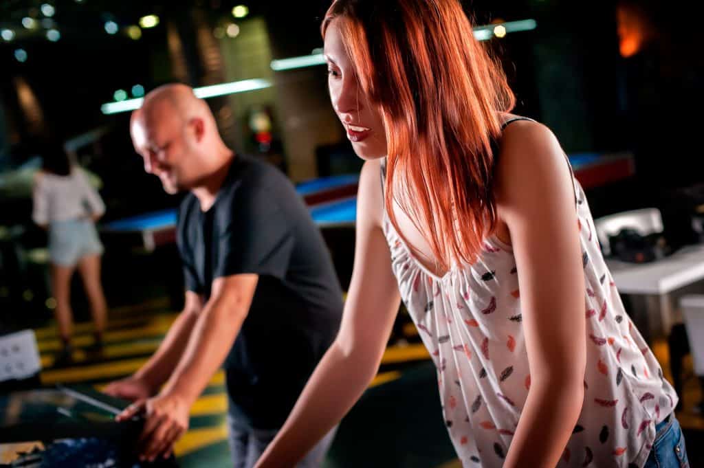 Young woman playing pinball in game room